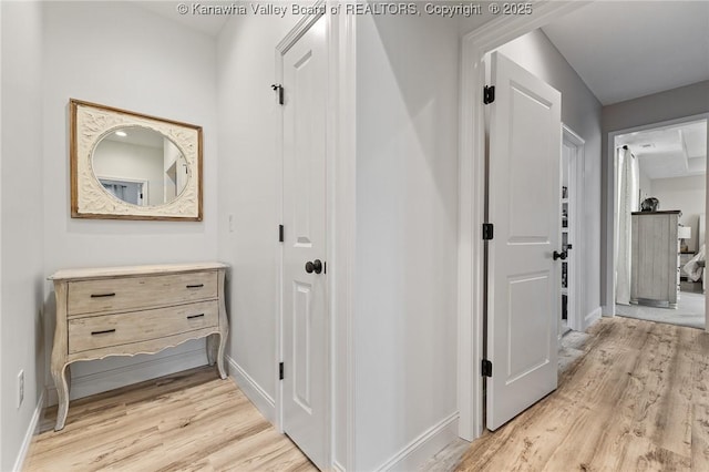 hall featuring light wood-type flooring and baseboards