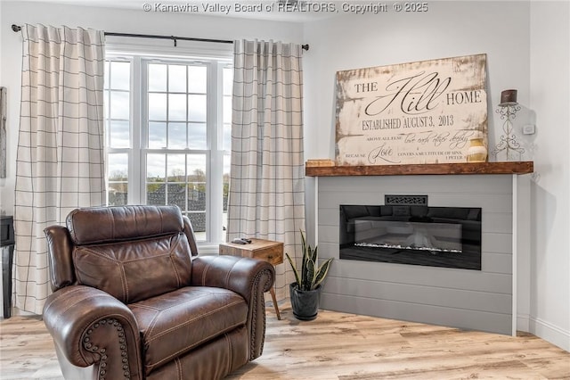 sitting room with wood finished floors and a glass covered fireplace