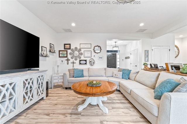 living room with light wood-type flooring, visible vents, and recessed lighting