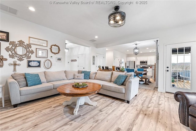 living area with light wood-style floors, recessed lighting, and visible vents