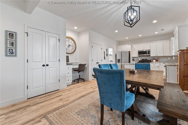 dining space with baseboards, light wood-style flooring, built in desk, a notable chandelier, and recessed lighting