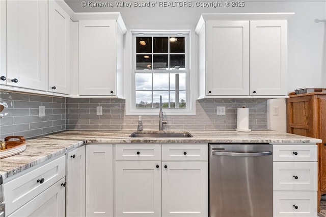 kitchen with backsplash, stainless steel dishwasher, white cabinets, a sink, and light stone countertops