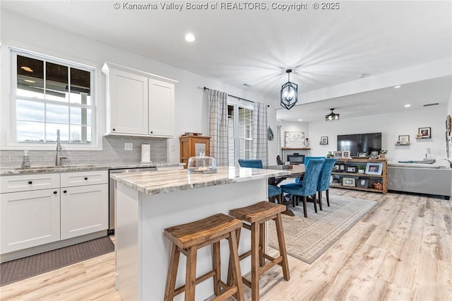 kitchen with light wood-style floors, tasteful backsplash, open floor plan, and a sink