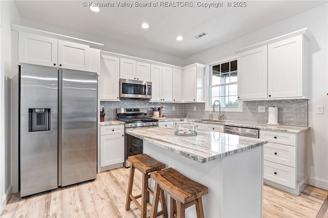 kitchen with light wood-style flooring, stainless steel appliances, a sink, visible vents, and white cabinets