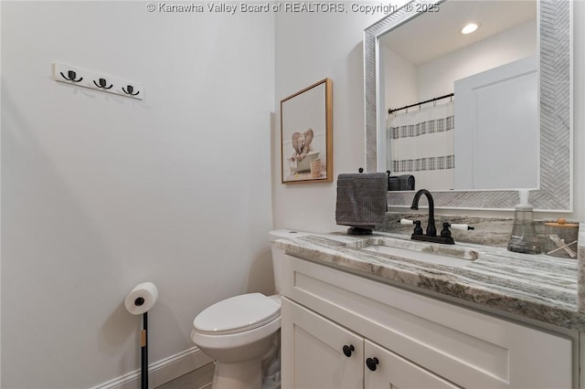 bathroom with toilet, baseboards, and vanity