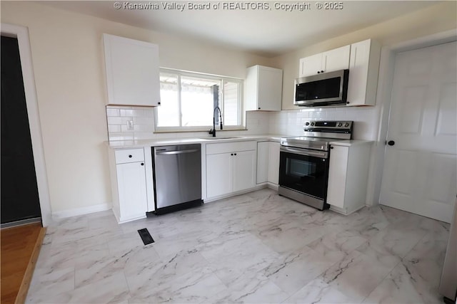 kitchen featuring marble finish floor, white cabinetry, appliances with stainless steel finishes, and a sink