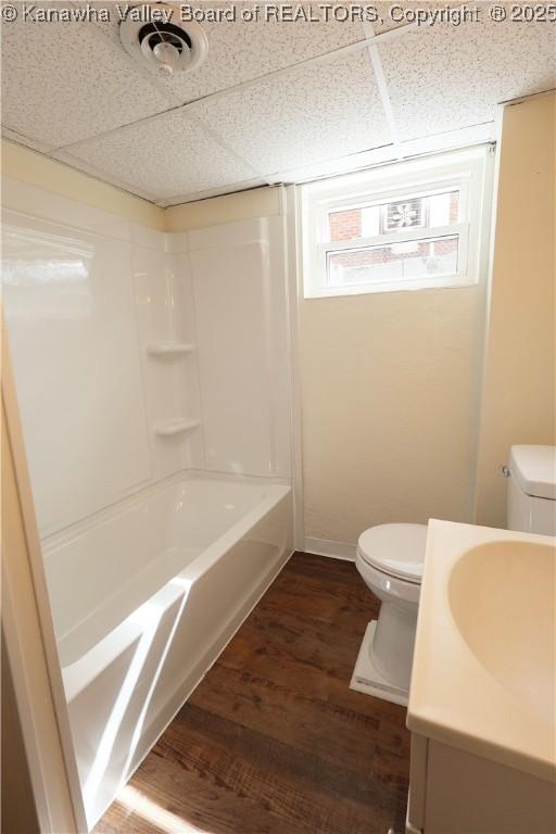 bathroom with toilet, a paneled ceiling, visible vents, and wood finished floors