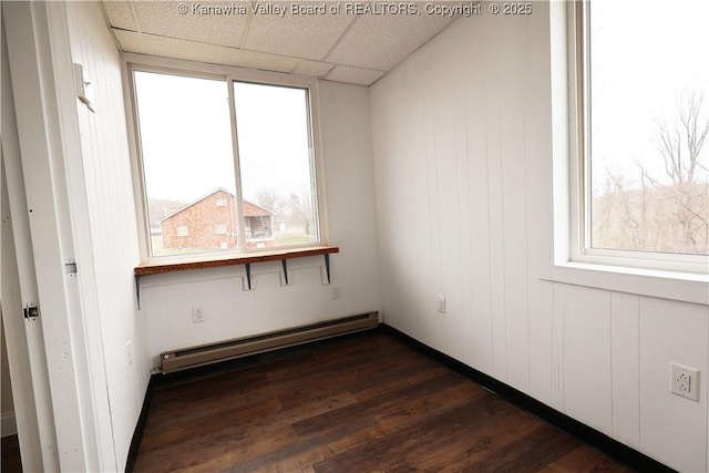 unfurnished room with a baseboard heating unit, a paneled ceiling, and dark wood-style floors