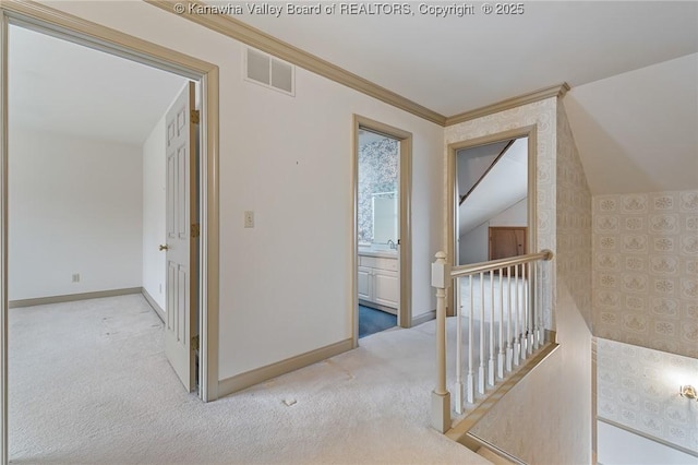 hallway with baseboards, visible vents, ornamental molding, an upstairs landing, and carpet floors