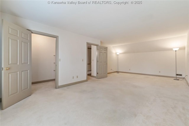 unfurnished bedroom featuring lofted ceiling, baseboards, and light colored carpet