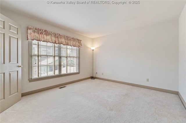 empty room featuring baseboards, visible vents, and light colored carpet