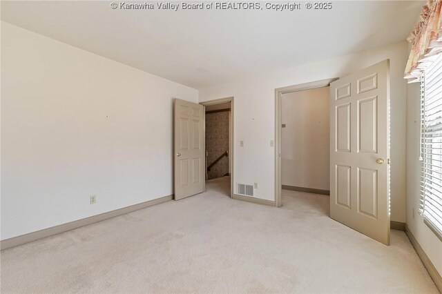 unfurnished bedroom featuring visible vents, light carpet, and baseboards