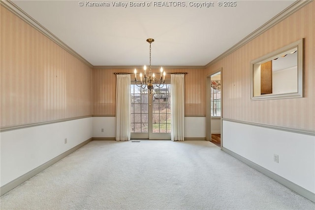 carpeted empty room with an inviting chandelier, baseboards, and crown molding