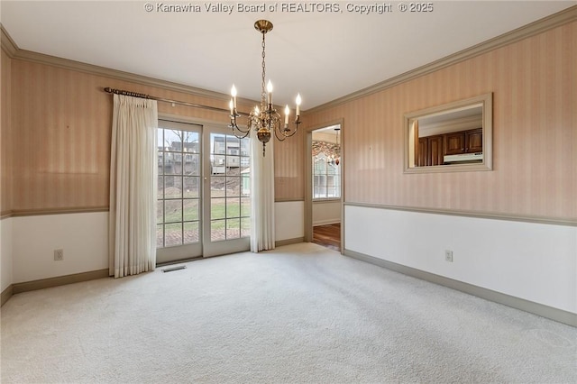 carpeted empty room with baseboards, visible vents, a chandelier, and crown molding