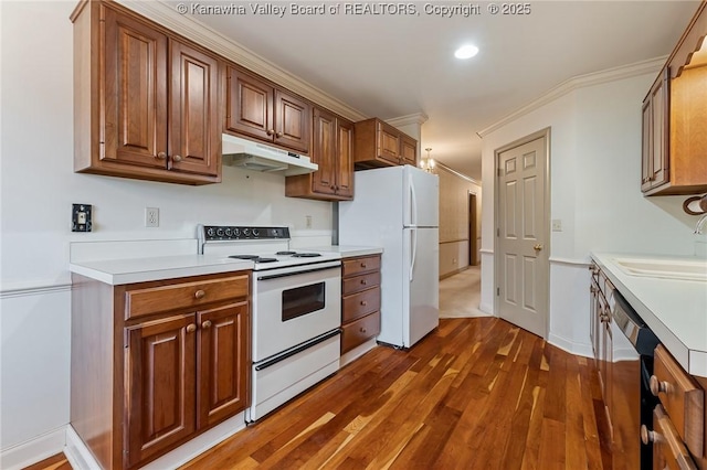 kitchen with white appliances, ornamental molding, dark wood-style flooring, light countertops, and under cabinet range hood