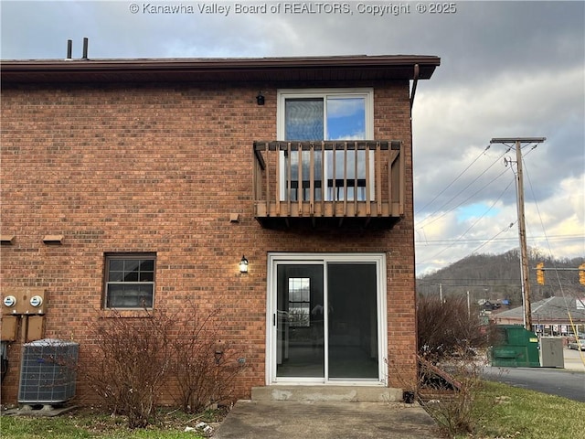 back of property with a balcony, central AC, and brick siding