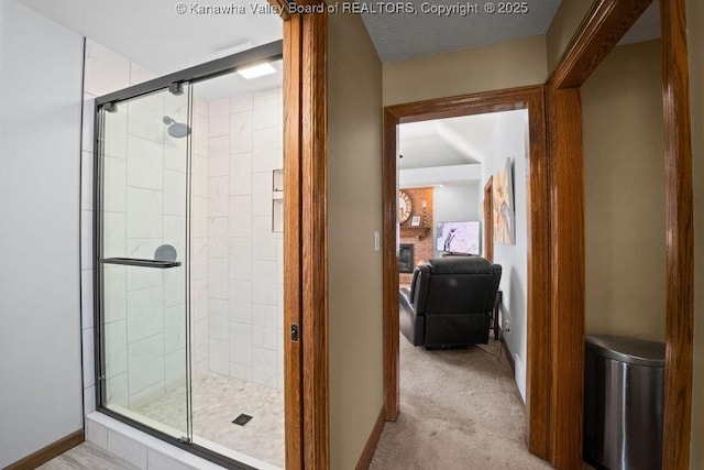 bathroom with a stall shower, a fireplace, baseboards, and connected bathroom