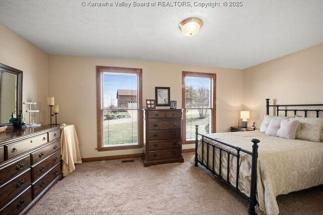 bedroom with light carpet, visible vents, multiple windows, and baseboards