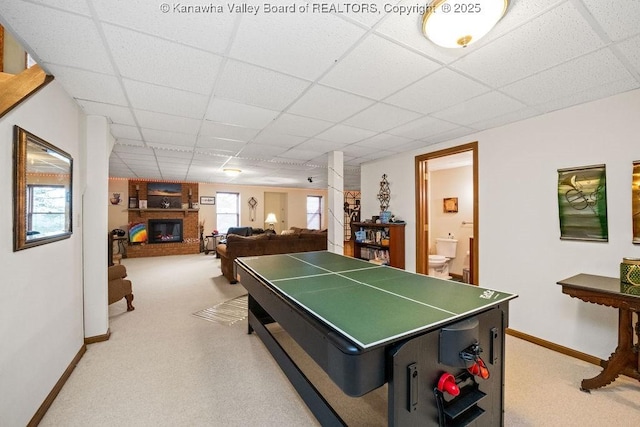 playroom featuring a paneled ceiling, light carpet, a fireplace, and baseboards