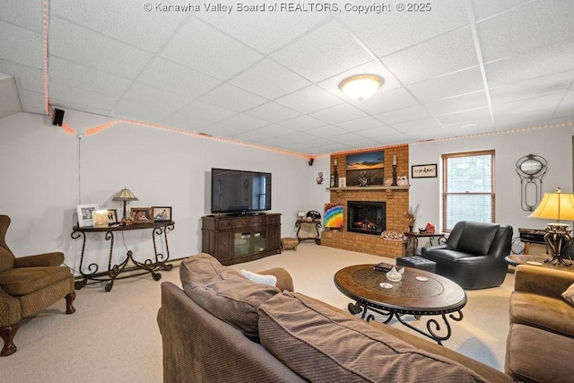 living room with carpet floors, a brick fireplace, and a drop ceiling