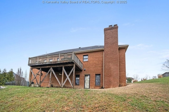 back of property featuring brick siding, a wooden deck, a chimney, and a yard