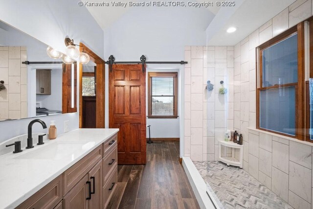 bathroom featuring lofted ceiling, walk in shower, wood finished floors, and vanity