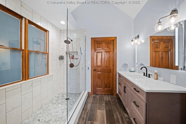 bathroom with lofted ceiling, a walk in shower, wood finished floors, and vanity