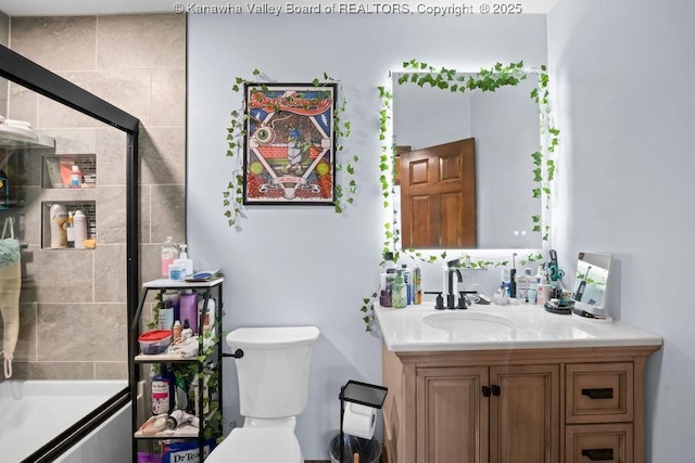 bathroom with toilet, tiled shower, and vanity