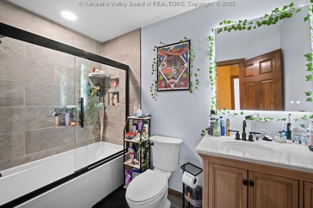 bathroom with vanity, toilet, and bath / shower combo with glass door