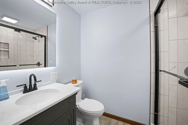 full bath with baseboards, toilet, wood finished floors, vanity, and a shower stall