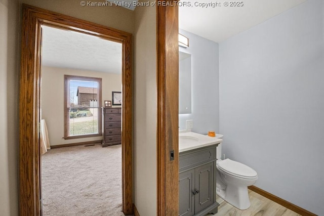 bathroom with toilet, baseboards, and vanity