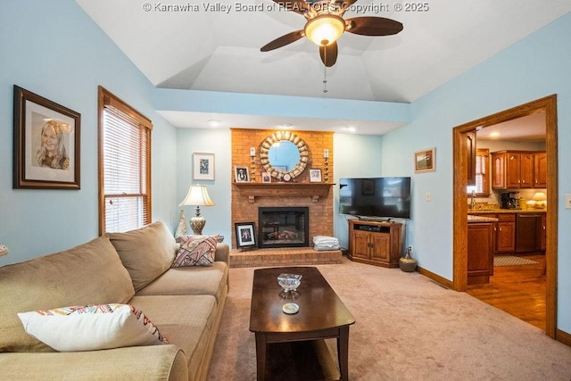 living room with a fireplace, carpet flooring, vaulted ceiling, ceiling fan, and baseboards