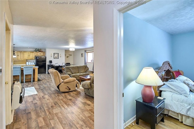 interior space featuring a textured ceiling, baseboards, and light wood-style floors