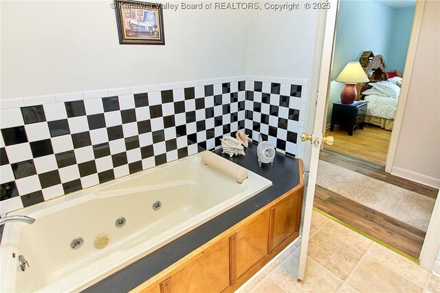 full bath featuring ensuite bath, a jetted tub, and tile patterned flooring