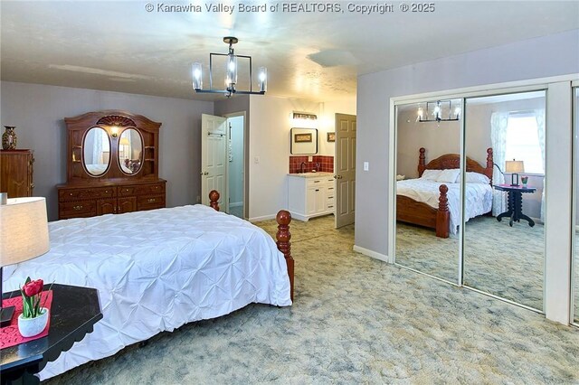 bedroom featuring carpet, a notable chandelier, a closet, ensuite bath, and baseboards