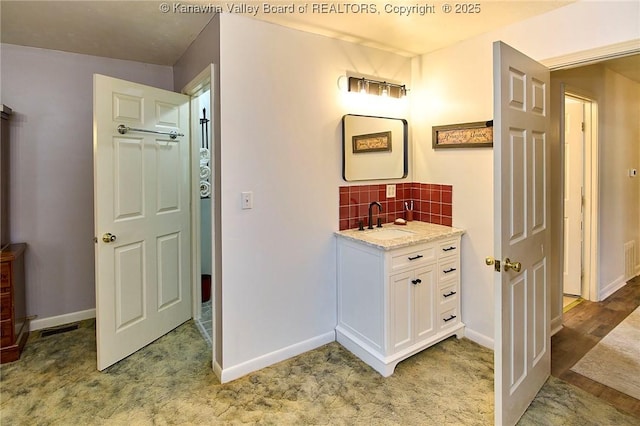 bathroom featuring backsplash, baseboards, and vanity