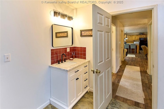 bathroom featuring wood finished floors, backsplash, and vanity