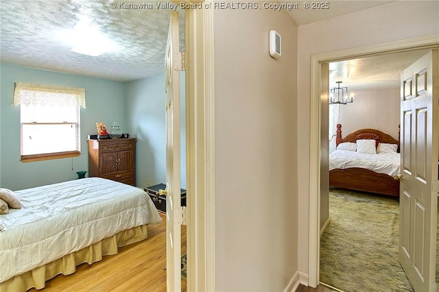 bedroom featuring a textured ceiling, wood finished floors, and baseboards