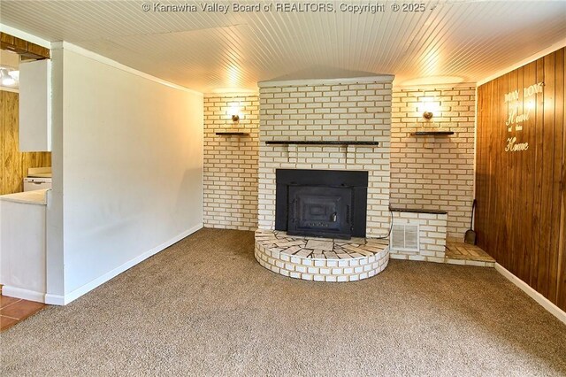 unfurnished living room featuring wooden walls, carpet flooring, visible vents, wood ceiling, and ornamental molding