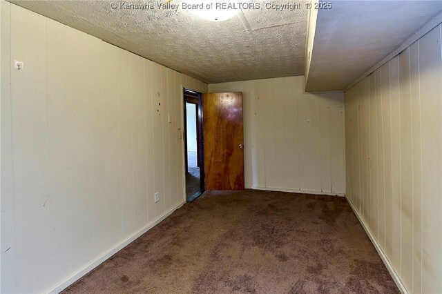 carpeted spare room featuring a textured ceiling and baseboards