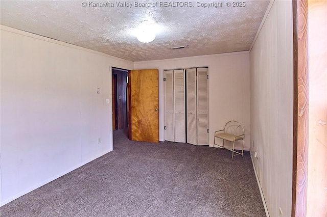 unfurnished room featuring a textured ceiling, carpet floors, visible vents, and crown molding