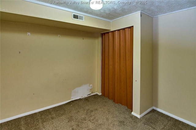 unfurnished room featuring a textured ceiling, carpet, visible vents, and baseboards