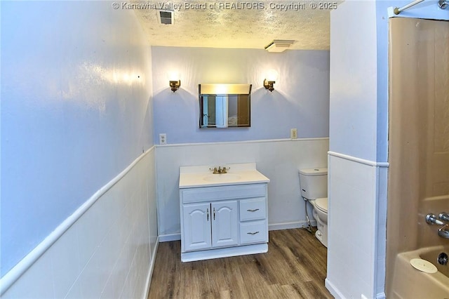 bathroom with toilet, a textured ceiling, vanity, and wood finished floors