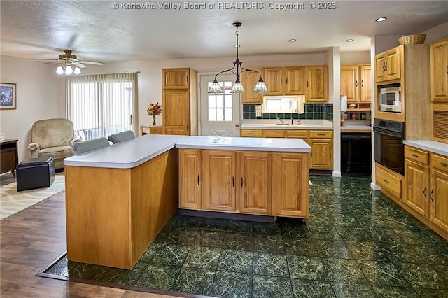 kitchen featuring light countertops, a healthy amount of sunlight, oven, and stainless steel microwave