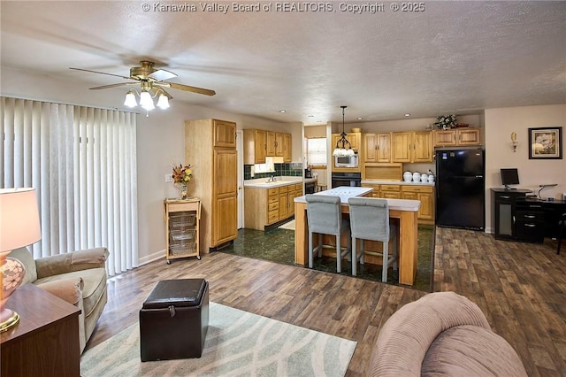 kitchen featuring a center island, light countertops, dark wood-type flooring, a textured ceiling, and black appliances