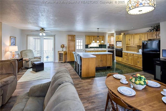 kitchen featuring open floor plan, light countertops, a center island, dark wood-style floors, and black appliances