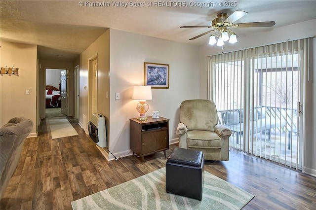 sitting room with baseboards, ceiling fan, heating unit, and wood finished floors