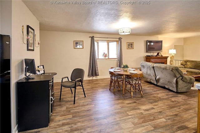 dining space with a textured ceiling, baseboards, and wood finished floors