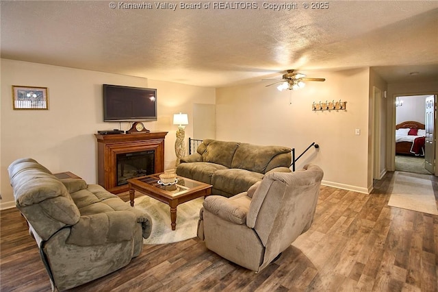 living area with a textured ceiling, wood finished floors, and a glass covered fireplace