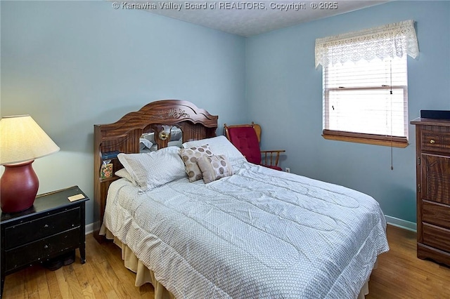 bedroom with baseboards and wood finished floors